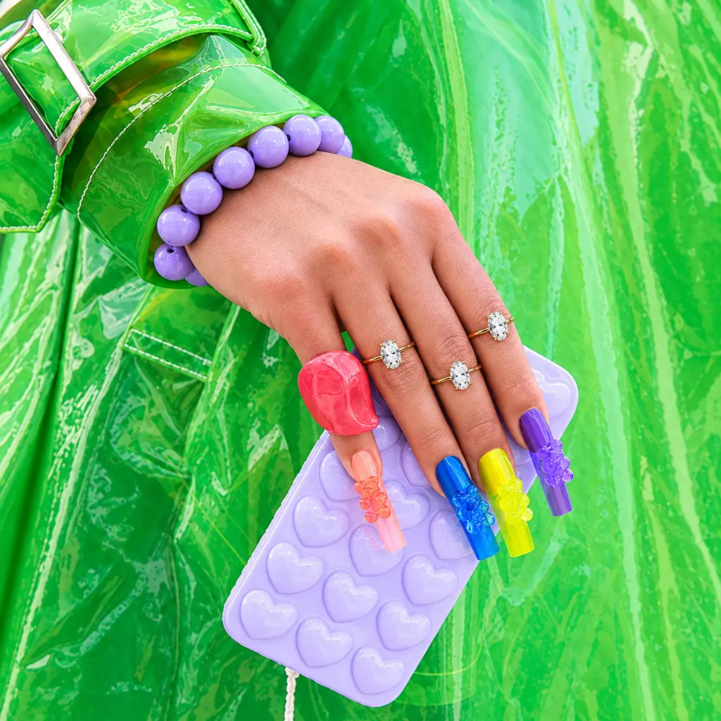 Three gold-colored solitaire-style rings styled with colorful candy nails | ANNIRO Jewelry